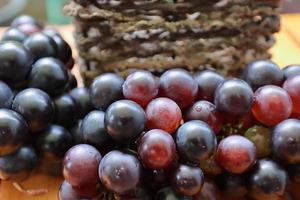 grappes de raisins violets mûrs sur fond en bois. tas de raisins rouges et noirs frais en arrière-plan. fruits de santé photo