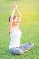 jeune femme faisant de l'exercice de yoga dans un espace extérieur de champ vert montrant calme paisible dans l'esprit de méditation - les gens pratiquent le yoga pour la méditation et le concept d'exercice photo