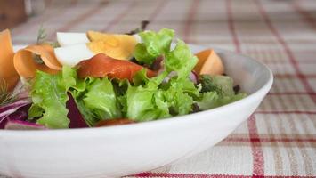 Salade saine de légumes de saumon frais sur une assiette blanche prête à manger - recette d'aliments sains et frais pour une utilisation en arrière-plan photo