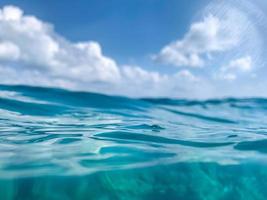 vue abstraite sur l'océan. surface de l'eau bleue de la mer ou de l'océan et sous l'eau avec un ciel ensoleillé et nuageux photo