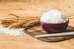 riz cuit dans un bol avec du grain de riz cru et du riz sec sur fond de table en bois. photo