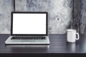 ordinateur portable avec écran blanc et tasse de café blanche sur le bureau photo