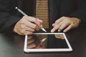 un homme d'affaires signe un contrat de tablette numérique en ligne dans l'application sur le bureau. photo