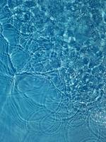 défocalisation de l'eau bleue floue qui brille dans la mer. fond de détail de l'eau ridée. la surface de l'eau dans la mer, le fond de l'océan. vague d'eau sous fond de texture de mer. photo