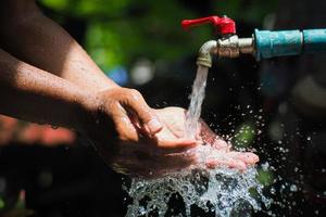 concept d'eau dans la vie quotidienne. mains soutenant l'eau qui coule du robinet. éclaboussures d'eau du robinet photo