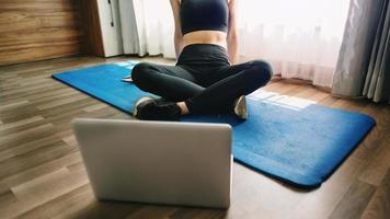 femme faisant de l'exercice à la maison et regardant des vidéos d'entraînement avec des haltères et regardant un ordinateur portable. femme en tenue de sport photo