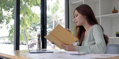 étudiante concentrée occupée à étudier à l'aide d'un ordinateur portable prendre des notes dans un cahier, un employé concentré écrire en regardant un webinaire ou un cours de formation en ligne sur ordinateur, concept d'éducation photo