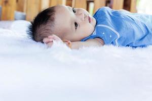 un beau bébé de 6 mois avec de grands yeux se trouve sur le lit. photo