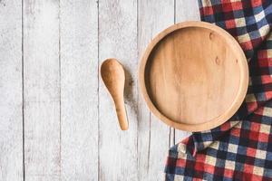 vue de dessus du disque en bois avec cuillère et nappe sur fond de table en bois photo