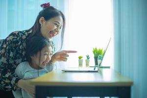 mère et fille utilisant un ordinateur portable tout en faisant un appel vidéo avec la connexion du père. photo