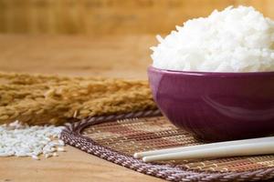 riz cuit dans un bol avec du grain de riz cru et du riz sec sur fond de table en bois. photo