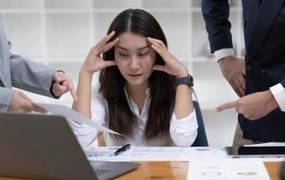 jeune femme d'affaires ou travailleuse asiatique frustrée et occupée travaillant avec ses collègues. photo