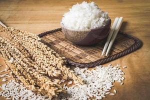 riz cuit dans un bol avec du grain de riz cru et du riz sec sur fond de table en bois. photo