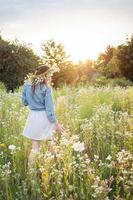 belle fille marchant sur le terrain en été avec des fleurs sauvages. photo