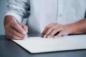 de jeunes cadres signent des documents pour des contrats commerciaux. les concepts de gestion des transactions et des documents comprennent la négociation d'entités corporatives et le remplissage de formulaires ou d'accords juridiques. photo