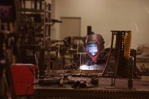 soudeur professionnel de l'industrie lourde travaillant à l'intérieur de l'usine, porte un casque et commence à souder. mise au point sélective photo