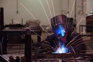 soudeur professionnel de l'industrie lourde travaillant à l'intérieur de l'usine, porte un casque et commence à souder. mise au point sélective photo