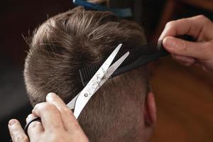 coiffeur coupe les cheveux de l'homme, coupe de cheveux moderne avec des ciseaux photo