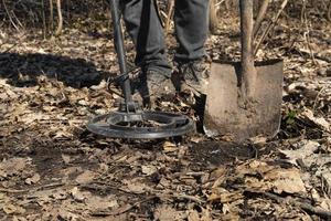 un homme recherche des pièces le long de vieilles routes à l'aide d'un détecteur de métal photo