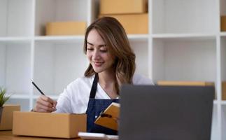 portrait d'une jeune femme asiatique sme travaillant avec une boîte à la maison le lieu de travail. propriétaire de petite entreprise de démarrage, entrepreneur de petite entreprise sme ou entreprise indépendante en ligne et concept de livraison. photo