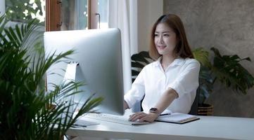 charmante femme d'affaires asiatique assise travaillant sur un ordinateur portable au bureau. photo