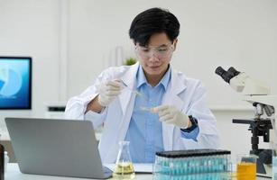 portrait de laboratoire de recherche médicale d'un beau scientifique masculin utilisant une tablette numérique, analysant des produits biochimiques liquides dans un flacon de laboratoire. photo