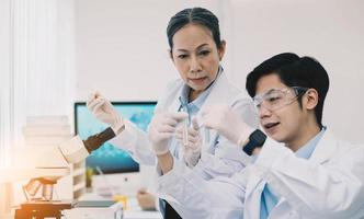 des scientifiques asiatiques travaillent dans un laboratoire de recherche scientifique en pharmacologie hospitalière. femme scientifique médicale et chercheurs travaillant en équipe analysant des vaccins innovants contre les virus dans un laboratoire de biologie des soins de santé photo