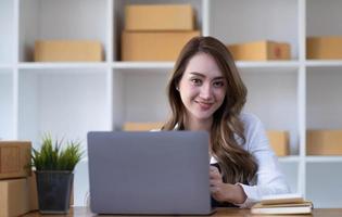 portrait d'une jeune femme asiatique sme travaillant avec une boîte à la maison le lieu de travail. propriétaire de petite entreprise de démarrage, entrepreneur de petite entreprise sme ou entreprise indépendante en ligne et concept de livraison. photo