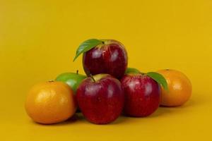 pomme rouge et oranges isolées sur fond jaune avec un tracé de détourage et toute la profondeur de champ pour la conception du concept de cuisine photo