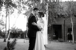 jeune couple le marié en costume noir et la mariée en robe courte blanche photo