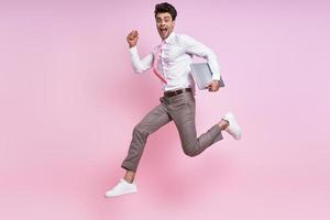 heureux jeune homme en chemise et cravate sautant sur fond rose photo