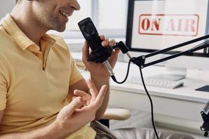 gros plan d'un homme méconnaissable utilisant un microphone lors de l'enregistrement d'un podcast en studio photo