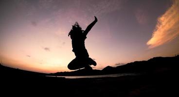 silhouette, happy jumping shadow girl sauter sur le ciel orange le soir photo