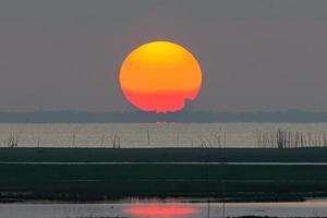 le grand lever de soleil est orange. lever de soleil sur la mer et la forêt de mangrove photo