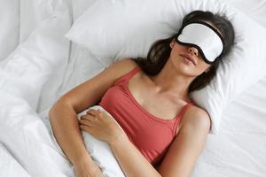 vue de dessus d'une belle femme portant un masque de sommeil en position couchée dans son lit photo