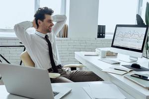 homme détendu tenant les mains derrière la tête alors qu'il était assis à son lieu de travail au bureau photo