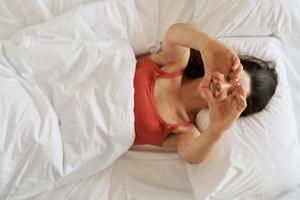 vue de dessus de la belle jeune femme gesticulant en forme de coeur et souriant en position couchée dans son lit photo