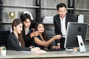 équipe multiage d'affaires réussie debout autour de l'ordinateur pour la présentation du travail. groupe de gens d'affaires lors d'une réunion au bureau, travaillant sur ordinateur photo