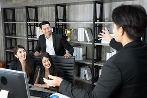 un groupe d'hommes d'affaires asiatiques se dit bonjour, au revoir les uns les autres au bureau. patron ou directeur souriant, femme d'affaires, homme d'affaires ou employé saluant dire bonjour photo