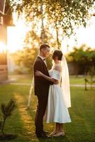 jeune couple le marié en costume noir et la mariée en robe courte blanche photo