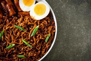 jjajang rabokki - nouilles instantanées coréennes ou ramyeon avec gâteau de riz coréen ou tteokbokki et œuf à la sauce aux haricots noirs photo