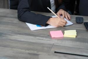 les gens d'affaires en costume écrivent sur un cahier ou un document. une femme d'affaires écrit une note