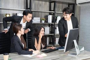 équipe multiage d'affaires réussie debout autour de l'ordinateur pour la présentation du travail. groupe de gens d'affaires lors d'une réunion au bureau, travaillant sur ordinateur photo