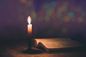 bougie avec bible sur une vieille table en bois de chêne. photo