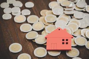 modèle de maison et piles de pièces d'argent sur fond de tableau flou. plans d'épargne pour la maison, le prêt, l'investissement, l'hypothèque, la finance et la banque sur le concept de maison.