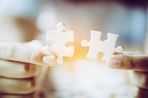 mains d'une personne petit enfant et parent jouant ensemble au jeu de pièces de puzzle sur une table en bois à la maison, concept de loisirs en famille, jouer avec le développement, l'éducation et le plaisir des enfants. photo