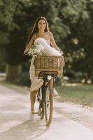 jeune femme avec chien bichon blanc frisé dans le panier de vélo électrique photo