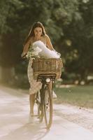 jeune femme avec chien bichon blanc frisé dans le panier de vélo électrique photo