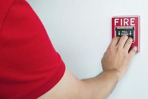 l'homme atteint sa main pour pousser la station d'alarme incendie photo
