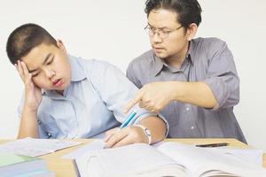 père asiatique enseignant sérieusement les devoirs à son fils de 14 ans photo